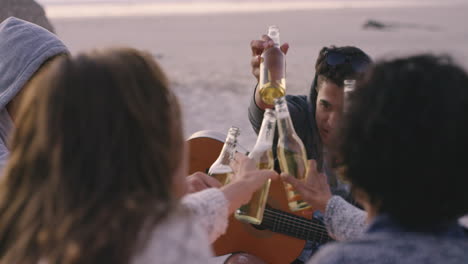fogata en la playa con un grupo de amigos, bebiendo cerveza y tocando la guitarra