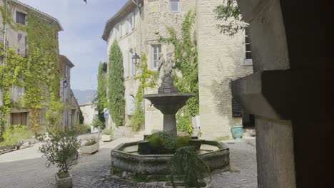 hermosa pequeña plaza romántica con fuente y pilar de figuras con viejas casas francesas en el fondo en buen tiempo