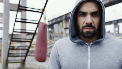 close-up view of handsome man with grey hoodie and looking with serious expression at the camera