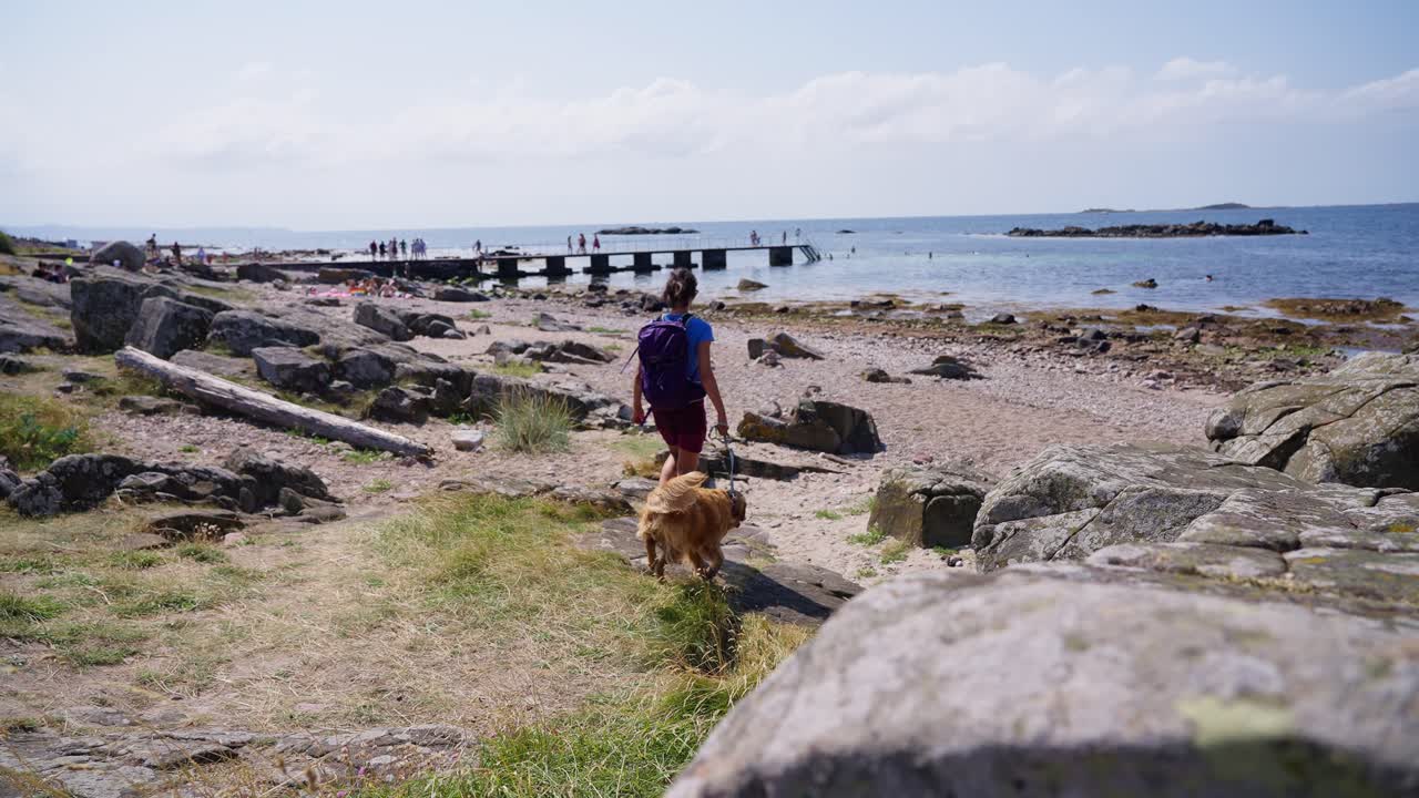 Rocky beach with a person walking in the background on a bright, sunny day