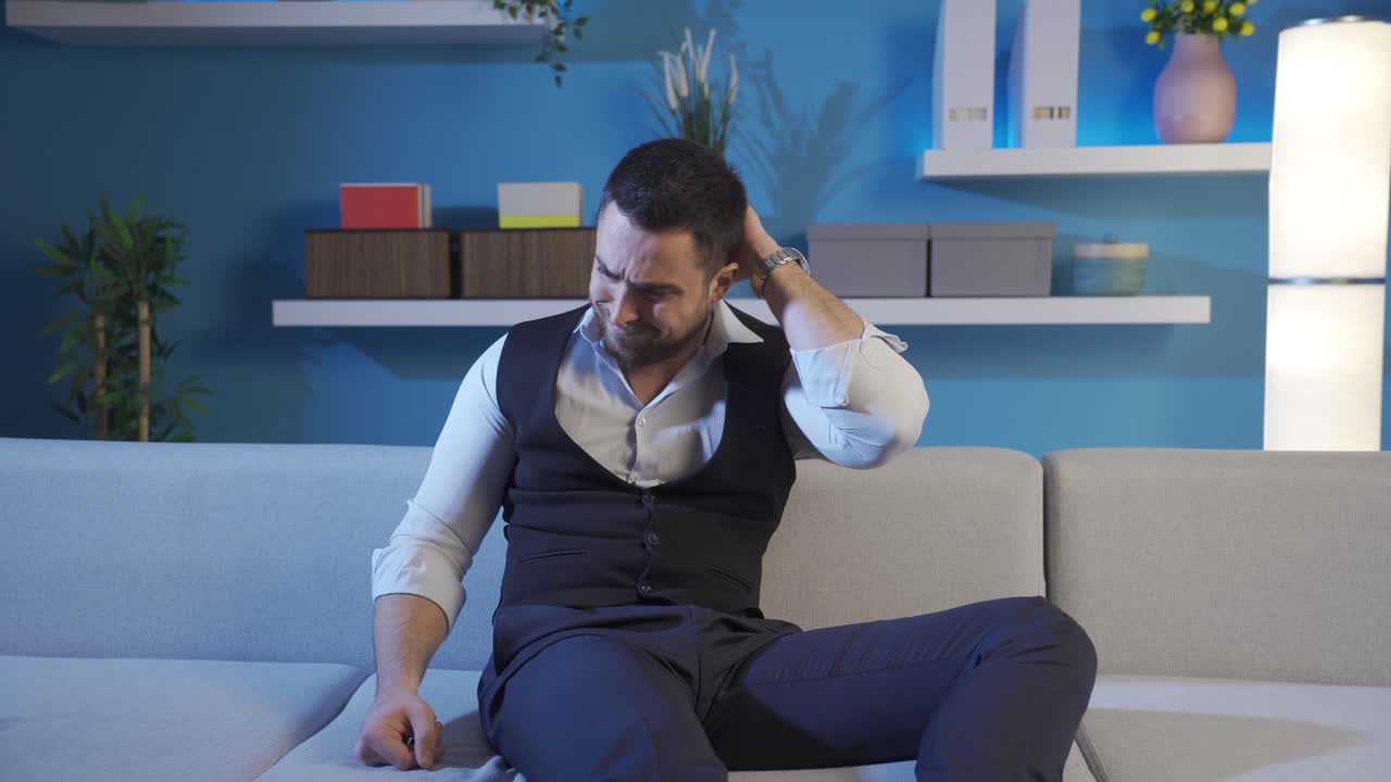 hombre sentado en casa mirando a su alrededor aburrido y preocupado.