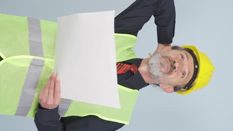 Vertical-video-of-Looking-up,-the-old-engineer-is-holding-his-hard-hat.