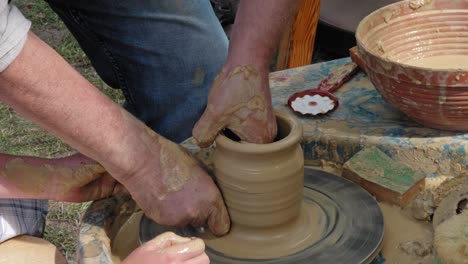 the boy and the traditional potter on the potter's wheel form a pot. they work outside. event. henheld.