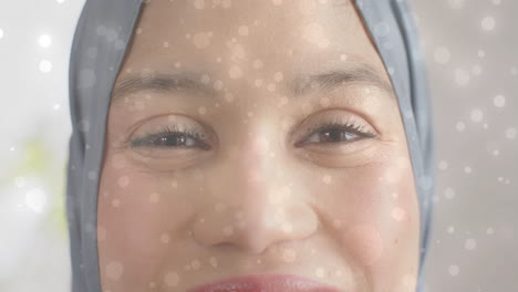 animation of light spots over biracial woman in hijab smiling