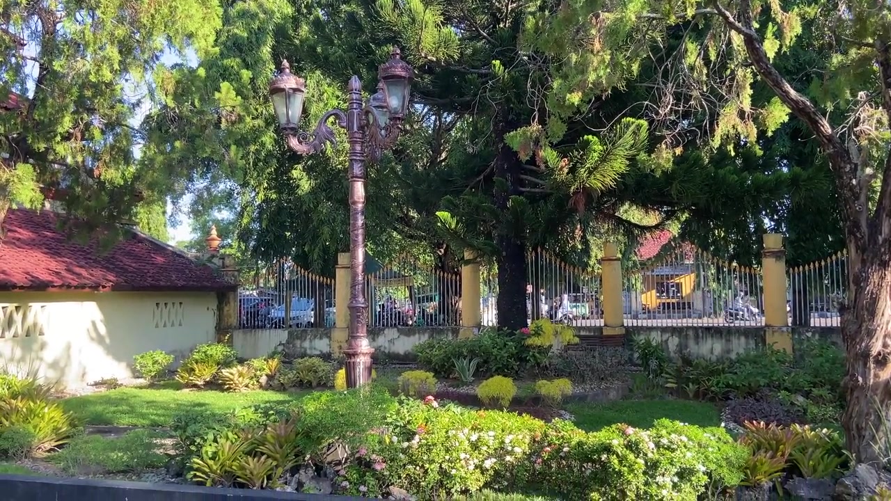 Taman Hijau Rimbun dengan Lampu Jalan Berukir dan Pohon pada Hari yang Cerah
