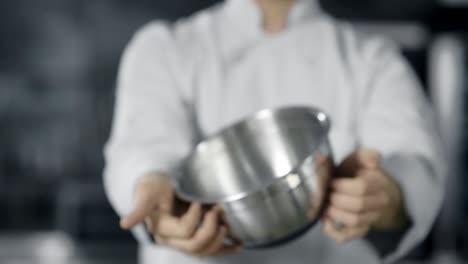 professional chef playing with kitchen tools. close up chef hands rolling bowl