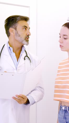 doctor taking notes in a report while assisting a patient