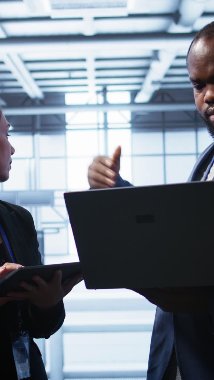 Uomo e donna afroamericani discutono di dati in una server room