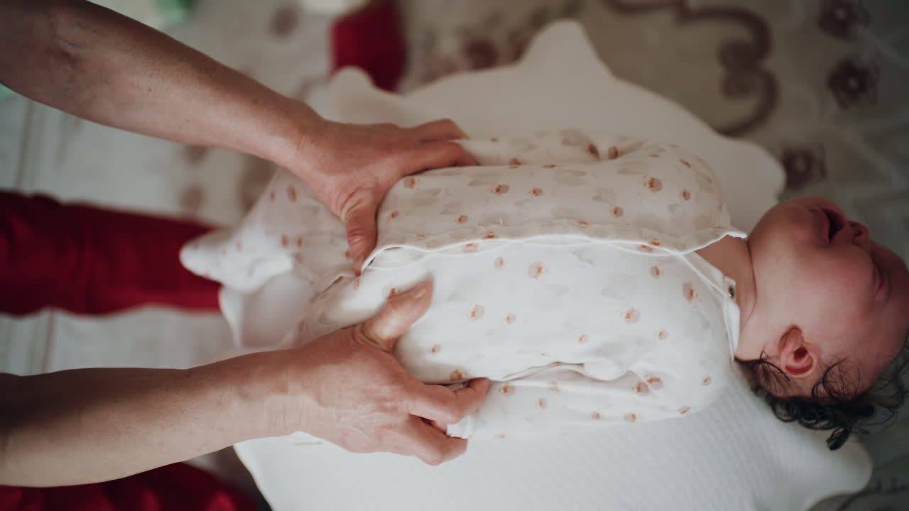 Baby placed on the back on a stability ball while adults support the infant's torso and shoulders