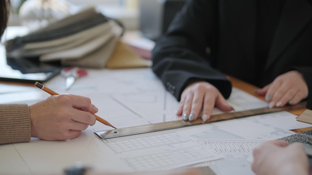 un equipo de diseñadores de interiores colabora en una mesa, examinando planes arquitectónicos, muestras de tela y paletas de colores, planeando un proyecto de diseño