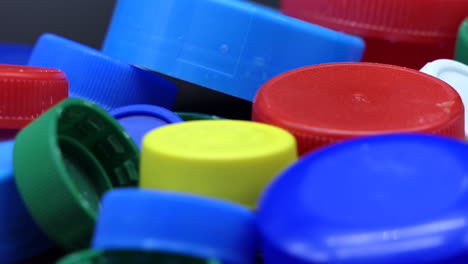 pile of multi colored plastic caps for recycling that slow rotate, low depth of field