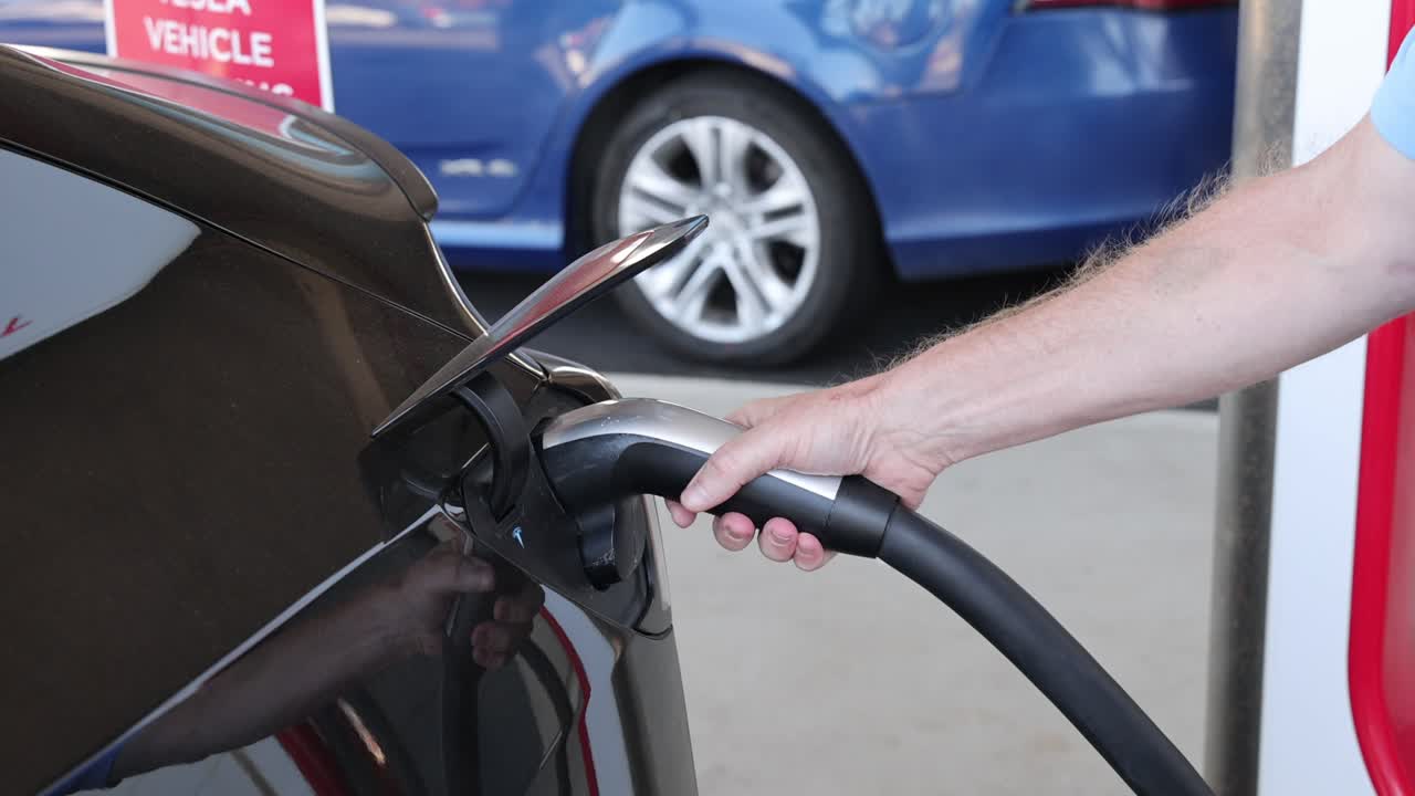 persona conecta el cargador al vehículo eléctrico