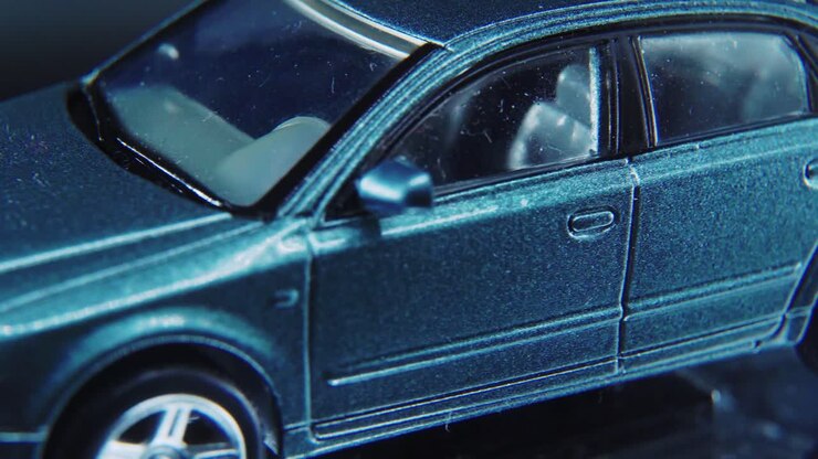 A tiny model metal sample car on a rotating stand with studio lights, macro close up shot, 4K video, silver wheels, black tires, doors and windows