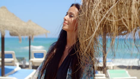mujer con un paraguas de playa mirando a la distancia