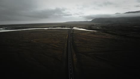 cinematic aerial car driving on ring road in mossy volcanic stone nature, moody dark landscape view iceland