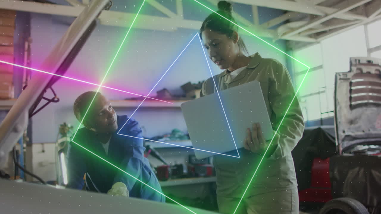 two women mechanics collaborating at engine bay in auto repair shop, displaying neon diagnostics