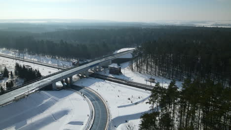 Vista-Panorámica-De-La-Vía-Férrea-Y-El-Paso-Elevado-A-Través-Del-Paisaje-Forestal-Durante-El-Invierno-En-Rakowice,-Cracovia,-Polonia---Toma-Aérea-De-Drones