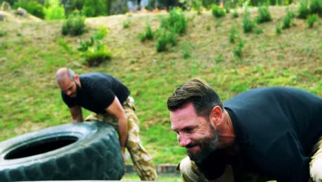 military men lifting a big tire