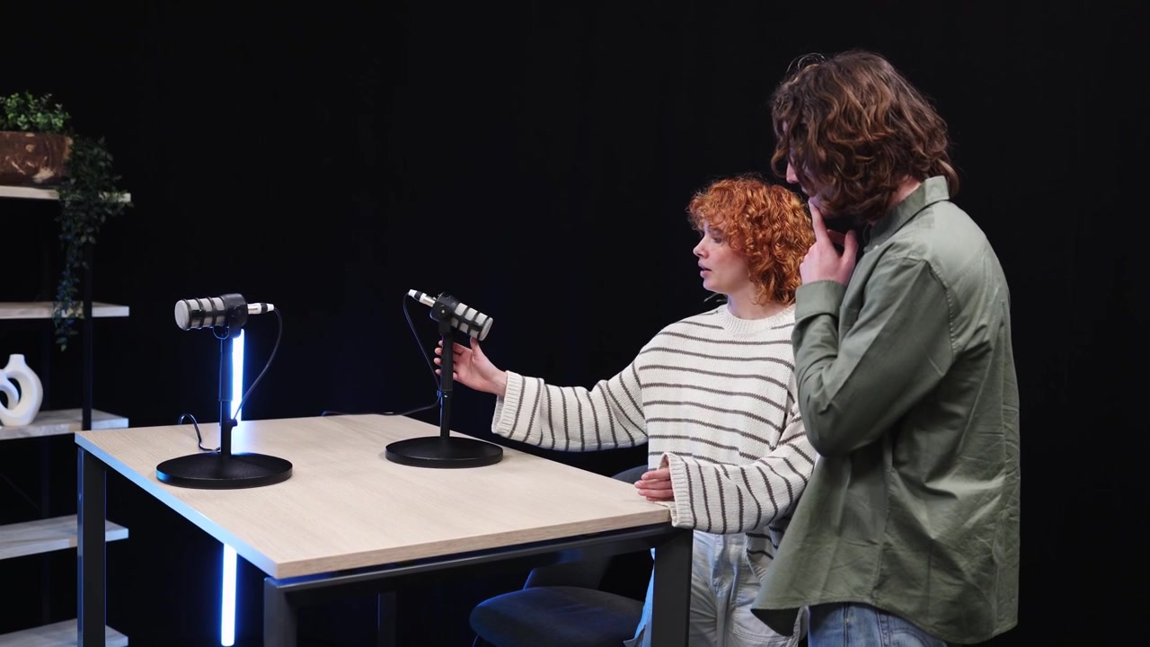 Kvinna och man sätter upp mikrofoner i en podcaststudio