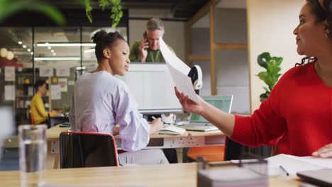 Happy-diverse-business-people-discussing-work-and-holding-documents-at-office