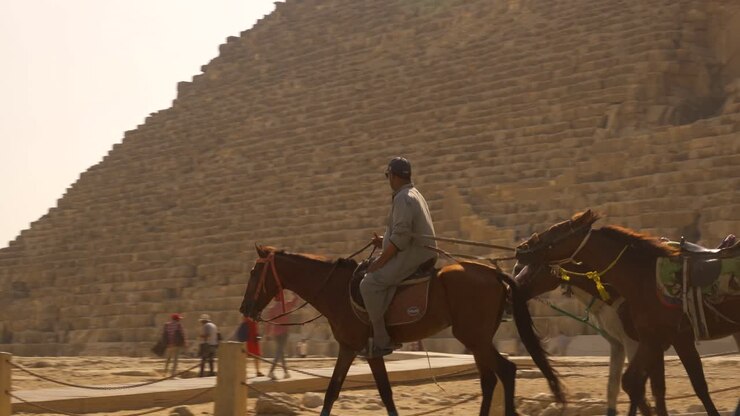 Homem andando a cavalo em frente a uma pirâmide