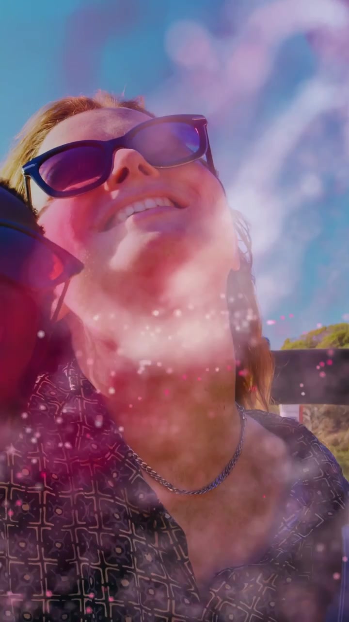 Video verticale: Due donne che si appoggiano all'indietro in un selfie di viaggio, con fumo rosa che si diffonde e rivela sorrisi.