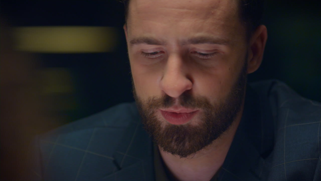 Homem sério conversando sob luz suave em encontro romântico no restaurante.