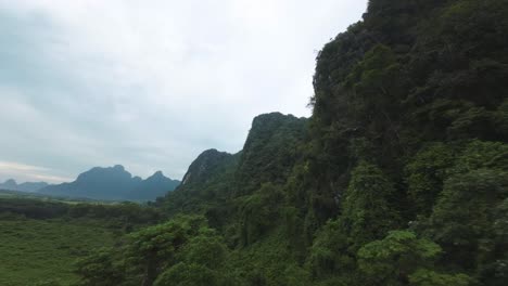 scenic aerial flight over blue lagoon, laos, featuring limestone cliffs and lush jungle under soft morning clouds
