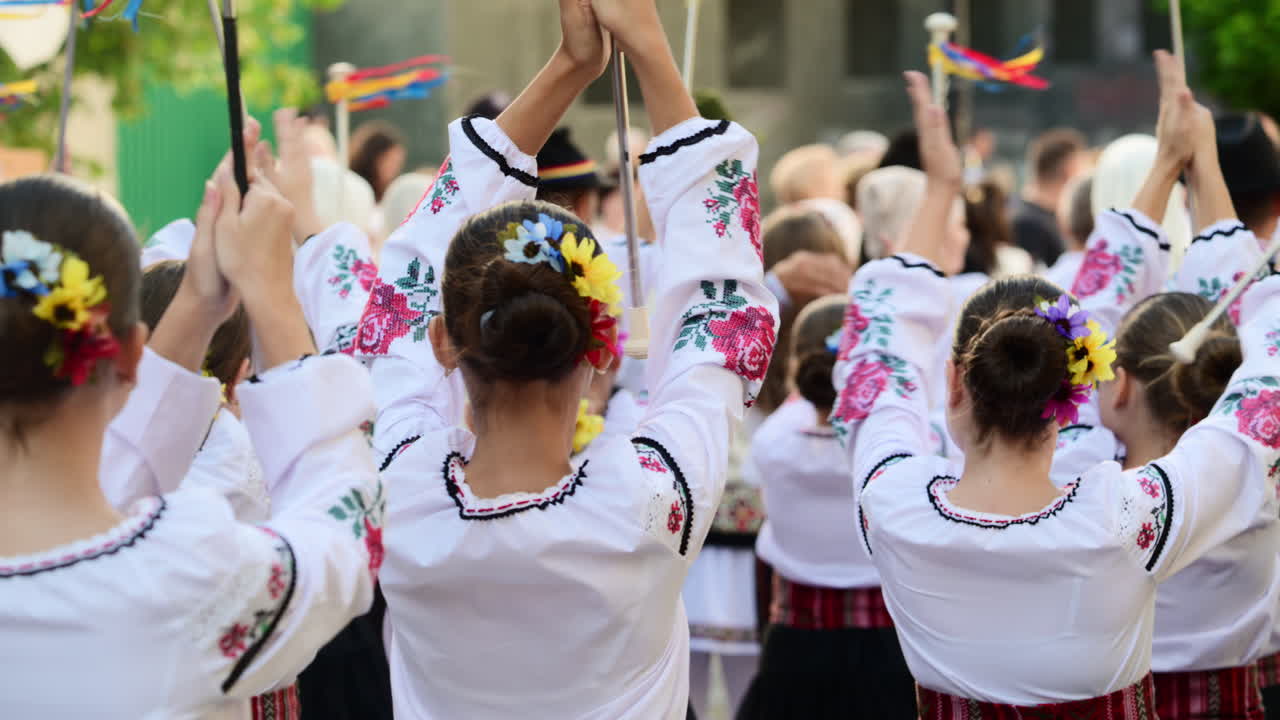 A group of dancers wearing embroidered garments joyfully performs traditional folk dance at a vibrant cultural festival outdoor