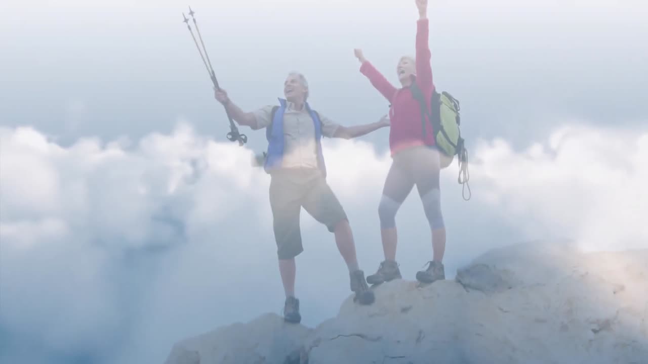 feliz pareja de ancianos caucásicos en la cima de las montañas sobre nubes de rápido movimiento