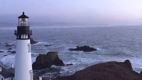 aerial forward toward yaquina lighthouse and waves breaking on rocks