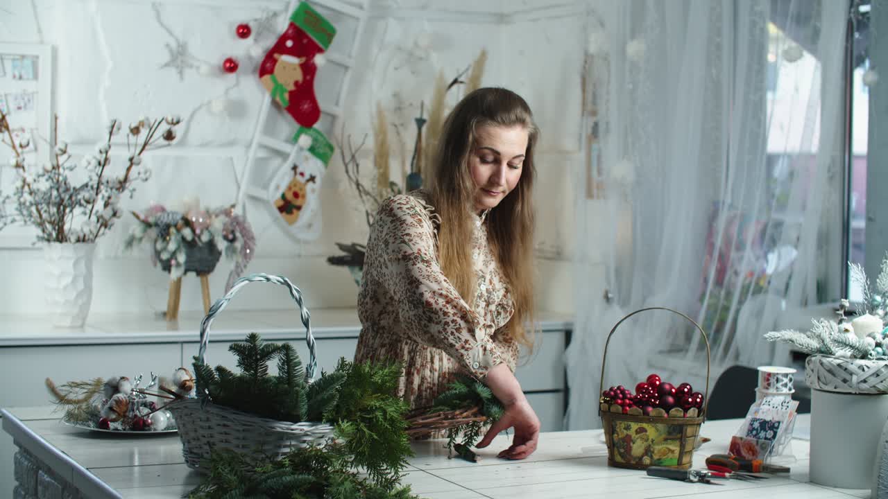 hacer una corona de navidad rústica. mujer sosteniendo ramas verdes sobre un fondo de madera rústica, taller de vacaciones de temporada en línea, haciendo decoraciones festivas en casa