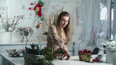 making rustic christmas wreath. woman holding green branches on rustic wooden background. seasonal holiday workshop online, making festive decorations at home