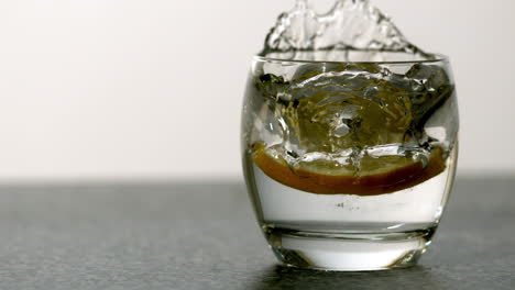 slice of orange falling into glass of water