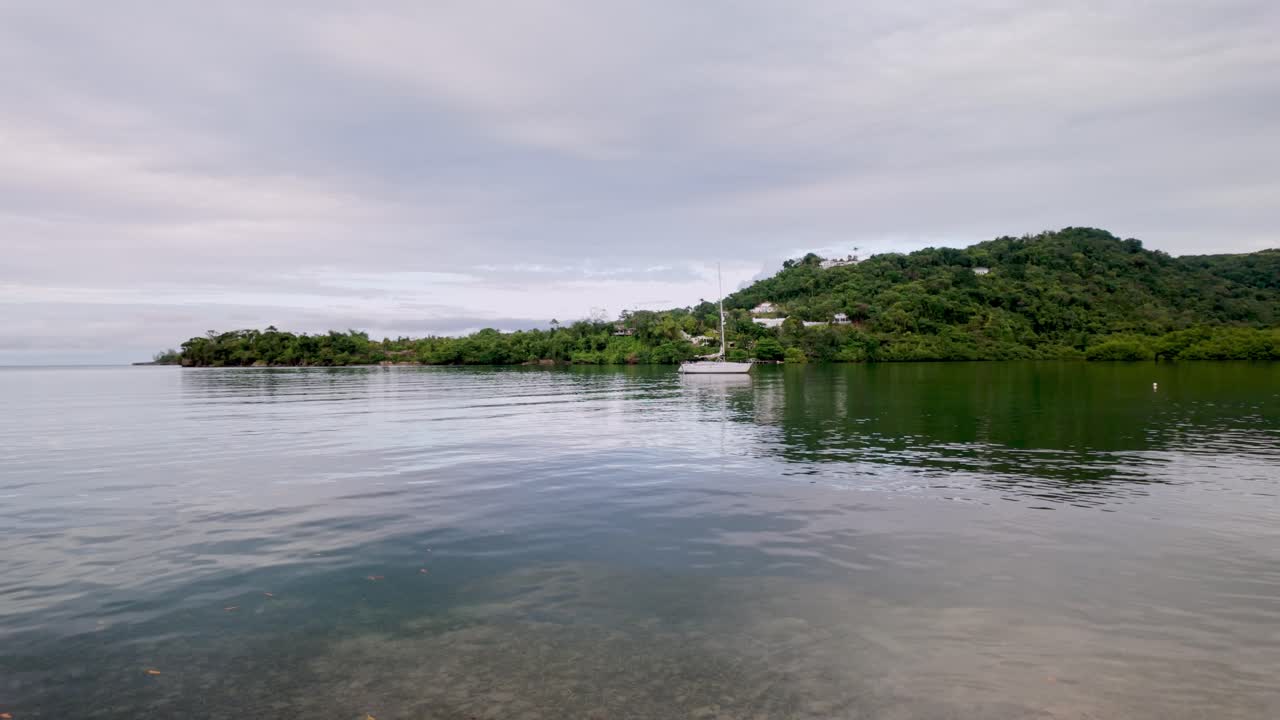 Small boat gently floating on calm, turquoise waters off the coast of Portland, Jamaica.