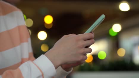 centrarse en la mano femenina usando el teléfono inteligente y publicando en las redes sociales.
