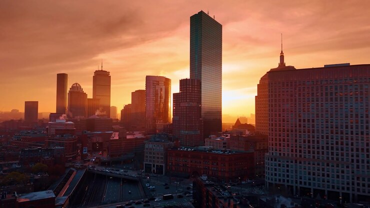 Grattacieli dello skyline di Boston colorati di arancione al tramonto. Riprese con drone sulla città scura al crepuscolo