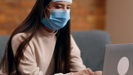 woman working on laptop while wearing a face mask