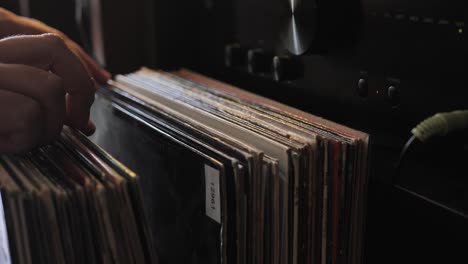 cerrar las manos del hombre hojeando discos de vinilo antiguos en casa