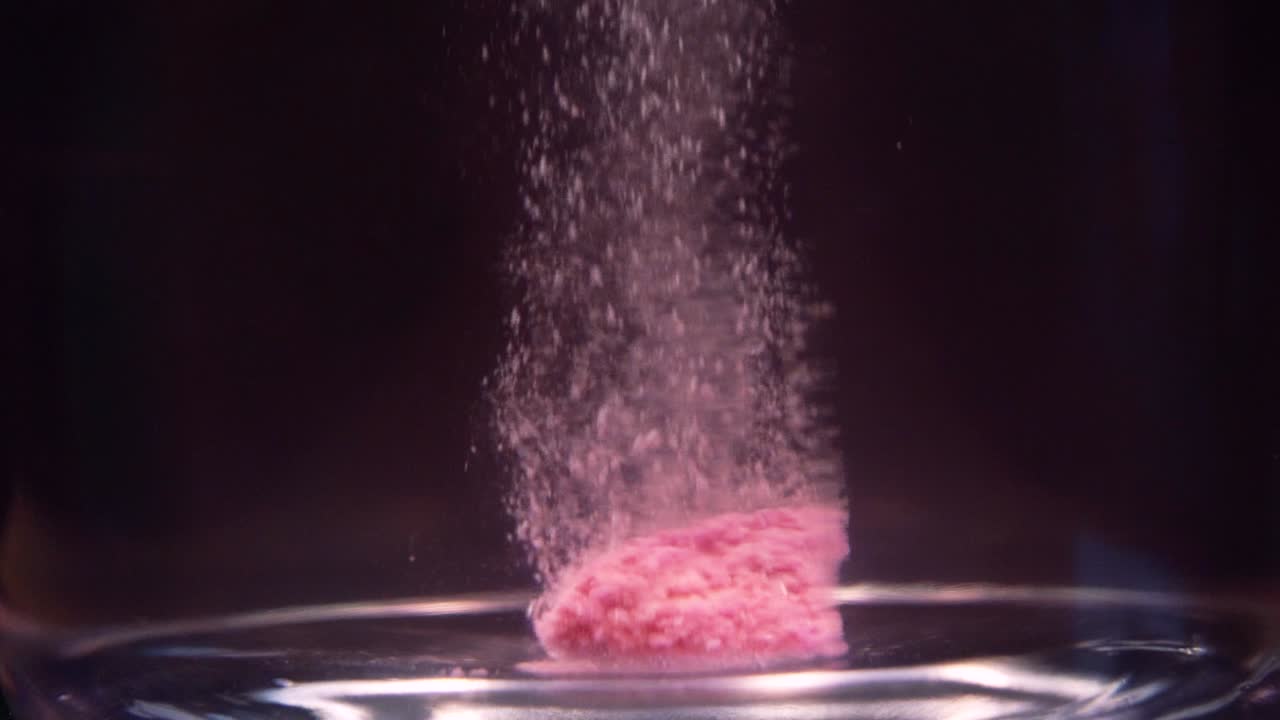 Slowmotion shot of efervescent pill dissolving in water. Bubbles going up. Stable shot with the Sony a7iii