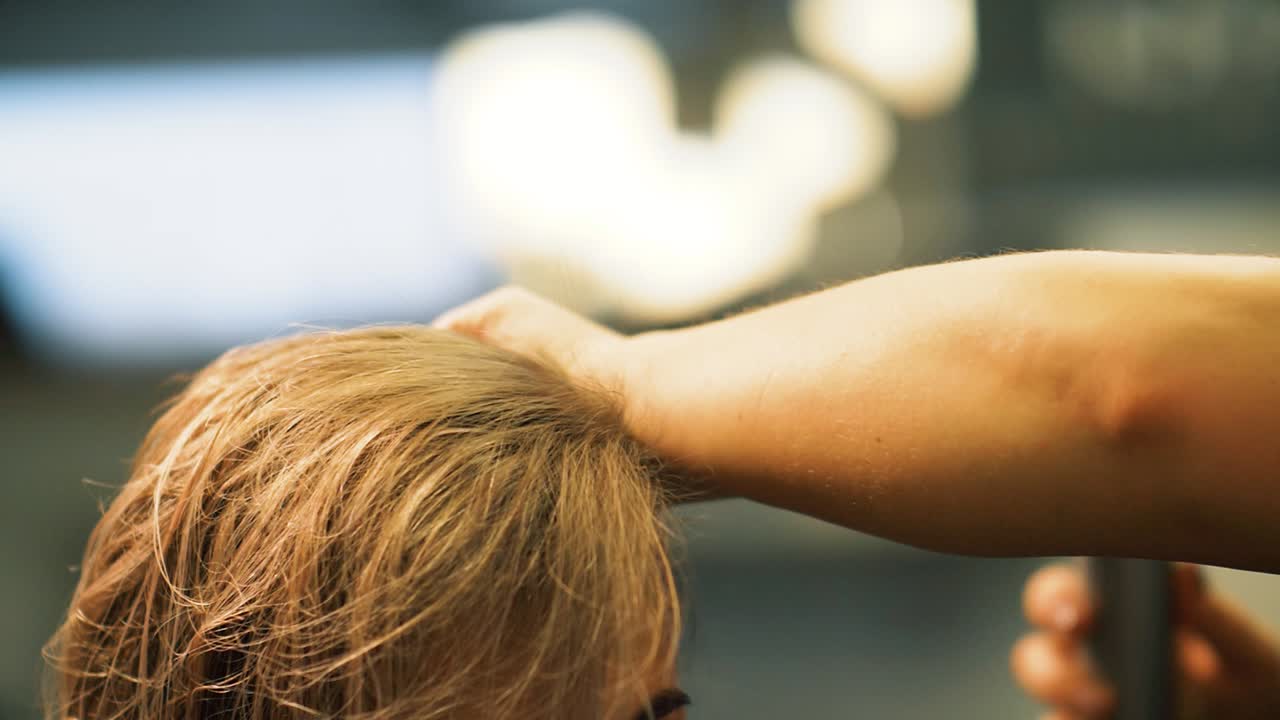 Close-up hair stylist is drying woman hair with mini blow dryer after washing and cutting. Slow motion.