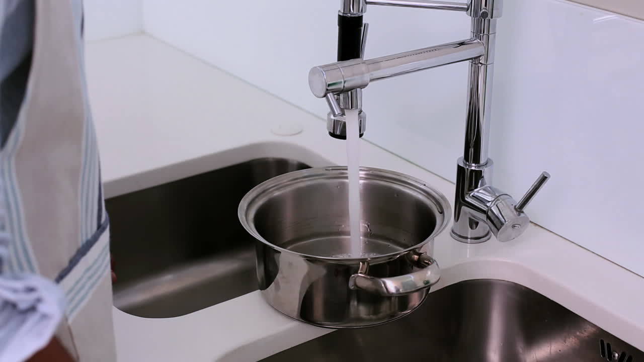 Uomo che riempie una pentola con acqua