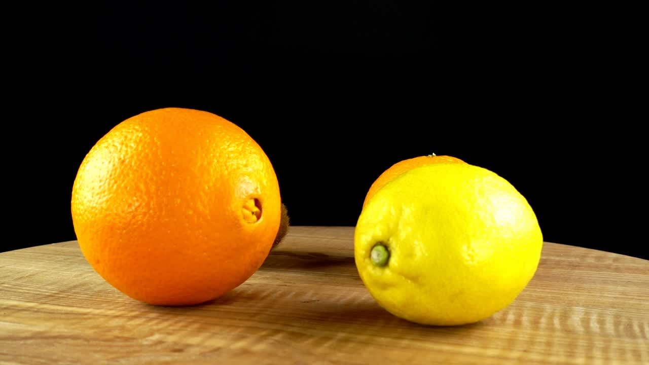 Mandarine, Orange, Zitrone und Kiwi auf schwarzem Hintergrund. Schneidebrett in Bewegung.