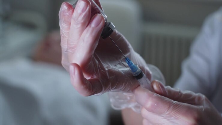 A health worker draws a solution from a bottle into a syringe