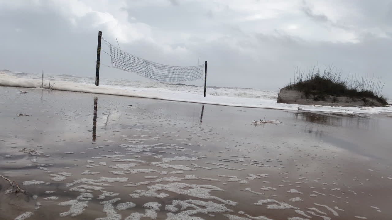 Beach volleyball court buried in sand from Hurricane Nicole storm surge in Florida