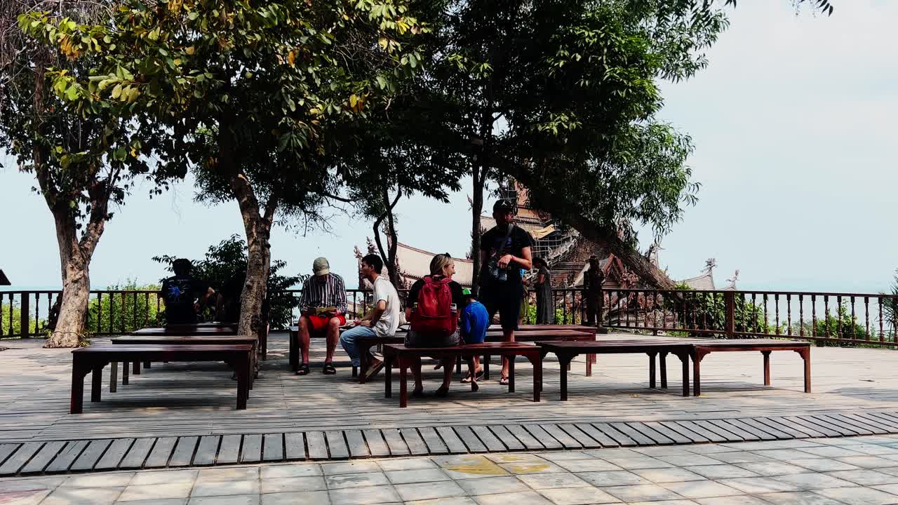 Tourists Relaxing on Benches with a View of a Temple
