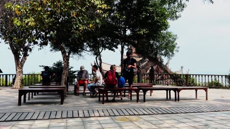 tourists relaxing on benches with a view of a temple