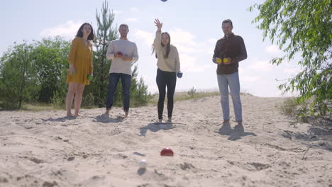 front view of caucasian group of women and men friends playing petanque on the beach