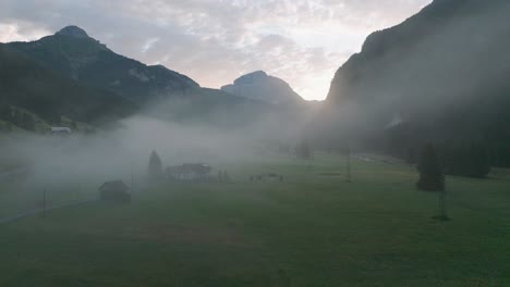 a sunrise drone flight through a valley slowly rising above the clouds to reveal the mountain range of the dolomites