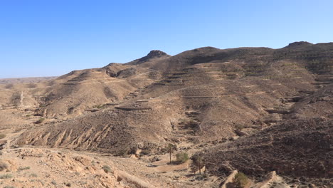 wide view of dry desert mountains under a bright blue sky in tunisia during the daytime